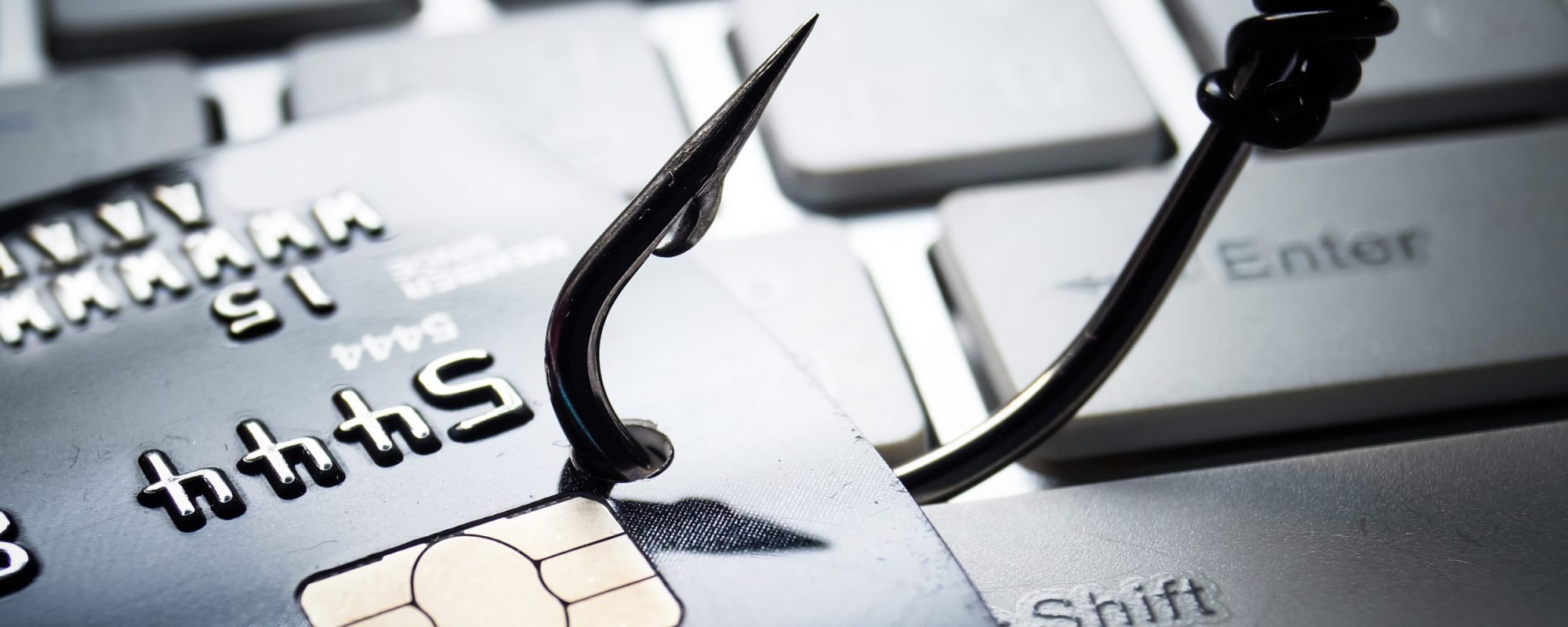 credit card phishing – piles of credit cards with a fish hook on computer keyboard administration illicite d’une plateforme en ligne